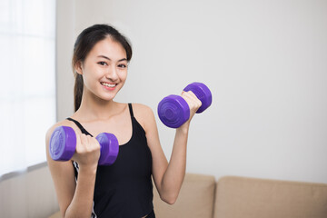 Fototapeta na wymiar Attractive asian young fitness woman lifting dumbbell weights workout at home in living room. Fresh feeling female training and exercise wearing sport wear fit body.