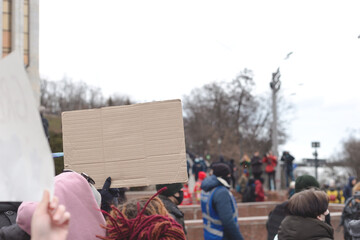 Woman holding poster in her hand against background of feminist protest. Copy space.