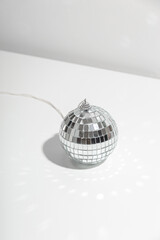 Gray disco ball lies on silver background with shadow.