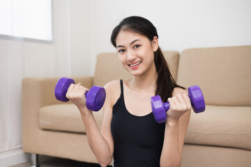 Fototapeta na wymiar Attractive asian young fitness woman lifting dumbbell weights workout at home in living room. Fresh feeling female training and exercise wearing sport wear fit body.