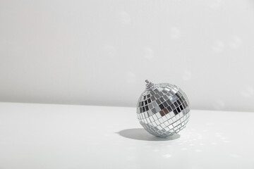 Gray disco ball lies on silver background with shadow. Copyspace.