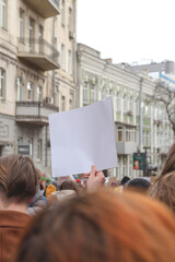 Woman holding poster in her hand against background of feminist protest
