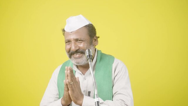 farmer indian politician greeting and giving fake promise to people in front of microphone during elections - concept of showing political strategy, lawmaker poll campaign and farmer supporter