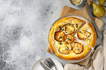 Homemade puff pastry pizza with pear, almonds, ricotta gorgonzola or blue cheese on the kitchen table. Delicious layered pie with pear, dorblu, nuts on a light culinary background top view