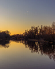 Sunset at coast of the river. Nature landscape with reflection, blue sky and yellow sunlight during sunset