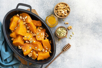 Healthy dessert or vegan lunch. Baked pumpkin. Delicious baked sweet pumpkin with nuts, pumpkin seeds and honey over gray stone background. Top view flat lay. Copy space.