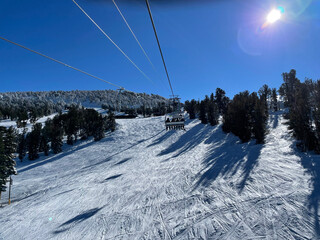View of chairlift and snow covered slopes at a ski resort on a bluebird winter day in Tahoe