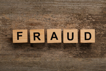 Fototapeta premium Wooden cubes with word Fraud on table, flat lay