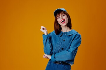 pretty woman in a cap and denim jacket posing yellow background unaltered