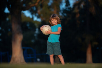 Little kid boy playing football in the field with soccer ball. Concept of children sport. Active ball games.