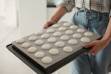 close-up of woman makes macaroons and puts it in the oven baked
