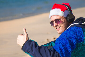 smiling man with christmas santa claus hat celebrating new year and christmas on the beach