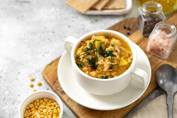 Pea soup with chicken in a white plate on a light cooking table