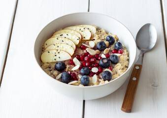 Oatmeal porridge with apple, pomegranate, blueberries and almonds. Healthy eating. Vegetarian food. Breakfast.