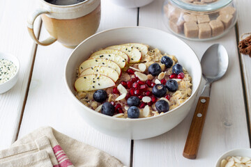 Oatmeal porridge with apple, pomegranate, blueberries and almonds. Healthy eating. Vegetarian food. Breakfast.