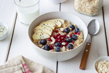 Oatmeal porridge with apple, pomegranate, blueberries and almonds. Healthy eating. Vegetarian food. Breakfast.