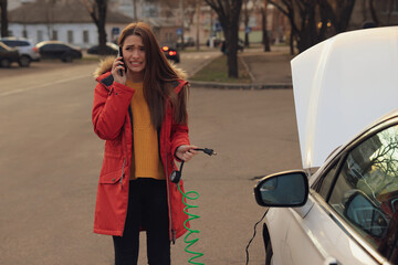 Fototapeta premium Young woman having difficulties while inflating car tire on street