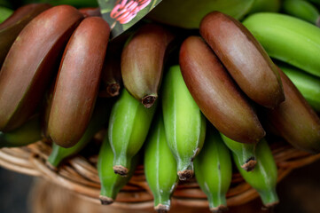 Red and green banana bunches in a fruit shop along the road