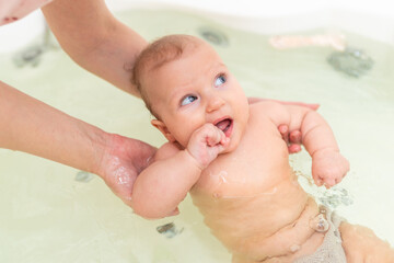 Mom holds the baby in her arms while bathing in the bathroom