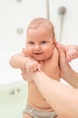 Cute woman bathes her toddler in the bathroom