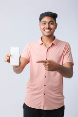 Young indian man showing smartphone screen on white background.