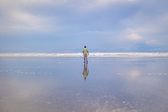 Man walking on the beach with reflection in cox's bazar, bangladesh
