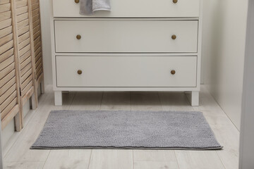 Grey bath mat near chest of drawers indoors