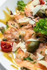 Fresh salmon carpaccio with parmesan cheese, capers, parmesan and cherry tomatoes. Food recipe...