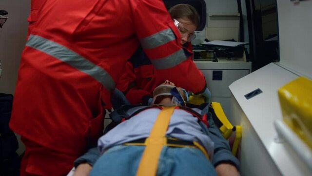 Mixed race paramedics taking care about patient in emergency vehicle