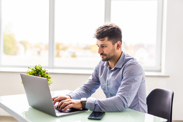 Portrait of young business man sitting at his desk in the office
