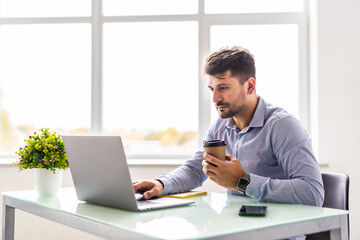 Handsome young businessman working with laptop in office