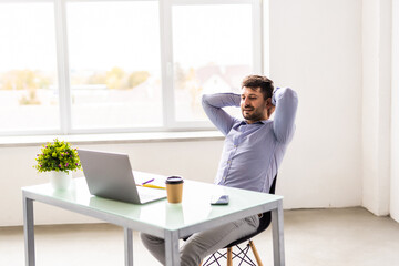 Young man smiling as he reads the screen of a laptop computer while relaxing