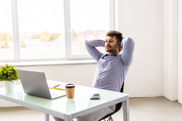 Young man smiling as he reads the screen of a laptop computer while relaxing