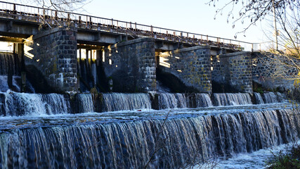 river dam. Dam water release, The excess capacity of the dam until spring-way overflows. streams of water, stone walls, a large construction of a dam on a reservoir