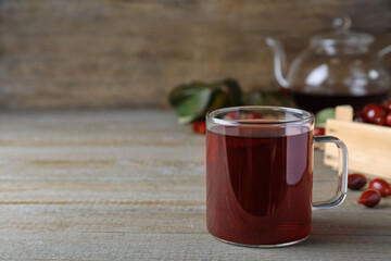 Glass cup of fresh dogwood tea on wooden table. Space for text