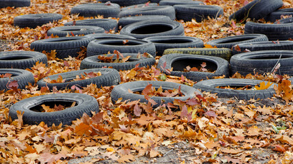 garbage from a heap of black old car tires among the trees in nature. environmental pollution....