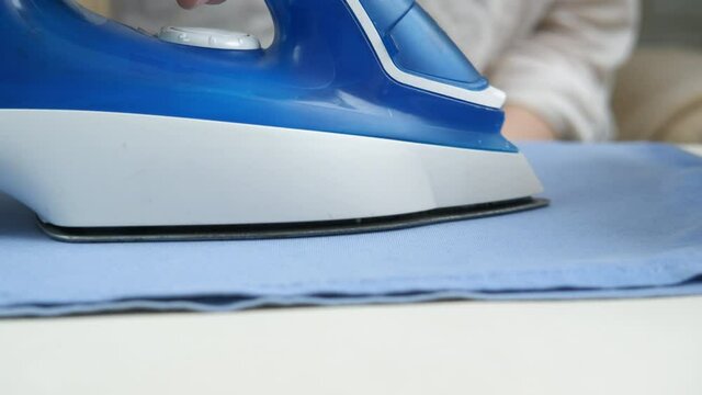 Iron close-up. Woman ironing clothes.