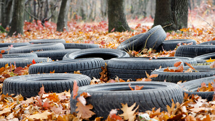 garbage from a heap of black old car tires among the trees in nature. environmental pollution. problems of ecology. car tires in autumn leaves, thrown into the forest. editorial, Ukraine, Kiev, 2021