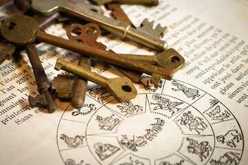 stacked old keys on the page of a French constellation book, フランス語の本 洋書 アンティークキー - obrazy, fototapety, plakaty