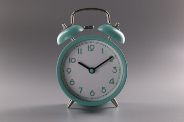 Single simple designed green retro clock on grey surface