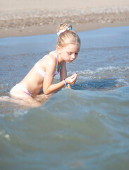 Little girl playing on the beach by the sea