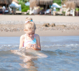Little girl playing on the beach by the sea