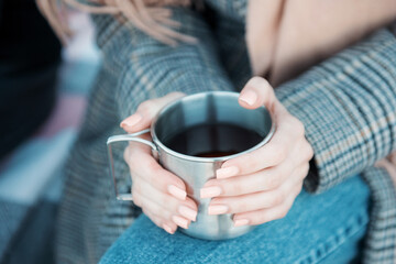 Young woman holding iron mug with hot tea