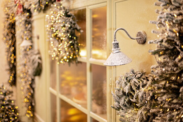 The snow-covered house is decorated for the new year. Vintage winter courtyard, decorated with Christmas trees, lanterns and a shop window with fresh baked goods. Soft selective focus.