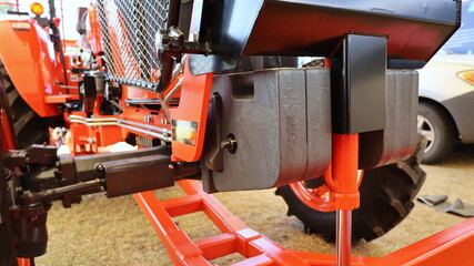 Tractor weight set. Metal counterweights are mounted in front of the tractor to balance the weight on the ground background. Selective focus