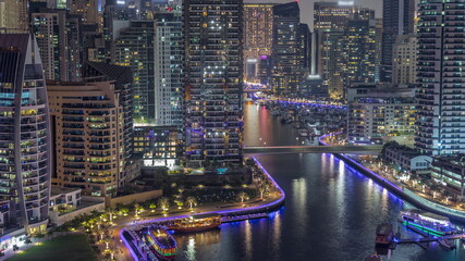 Fototapeta na wymiar Dubai Marina with several boat and yachts parked in harbor and skyscrapers around canal aerial night timelapse.
