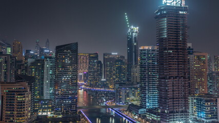 Fototapeta na wymiar Dubai Marina with several boat and yachts parked in harbor and skyscrapers around canal aerial night timelapse.