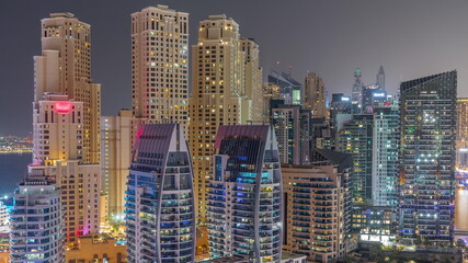 Dubai Marina skyscrapers and JBR district with luxury buildings and resorts aerial timelapse during all night with lights turning off
