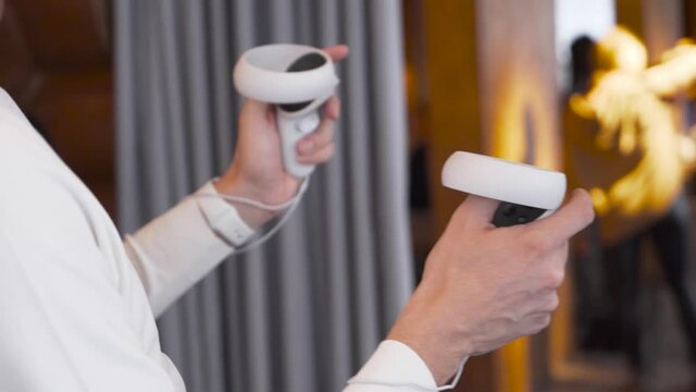 Young man wearing virtual reality headset draws abstract lines and figures with joysticks controllers close up. Augmented Reality. Shot on 4K