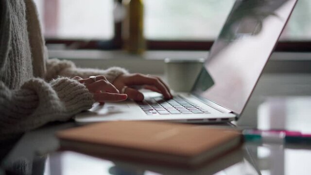 Close up shot of female hands typing on laptop keyboard and using a touchpad.